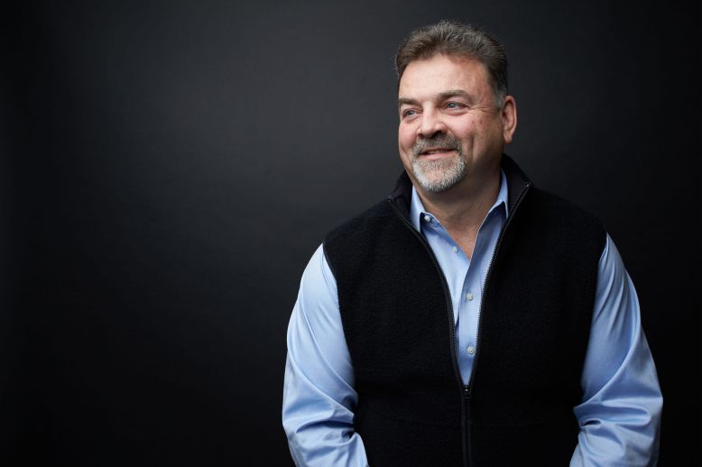 Professional headshot of man against dark background
