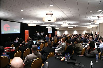 Large indoor event space with audience seated and Tanium branding visible
