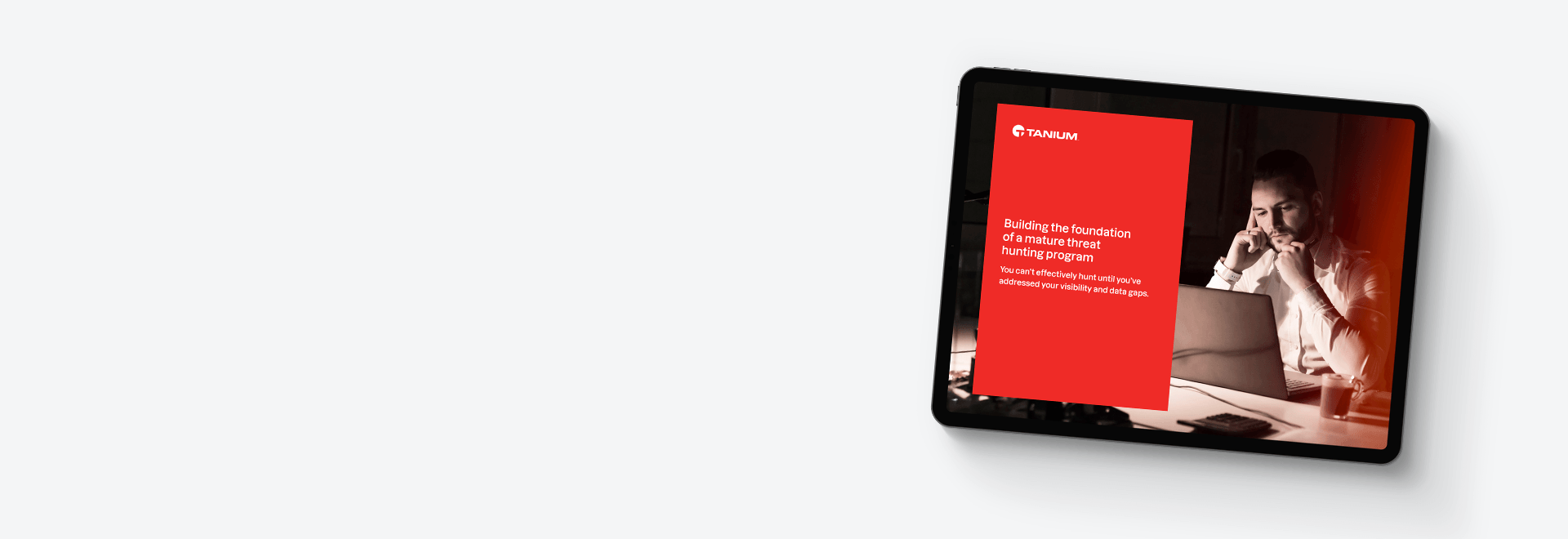 Tablet mockup of "Building the foundation of a mature threat hunting program" eBook with person at desk